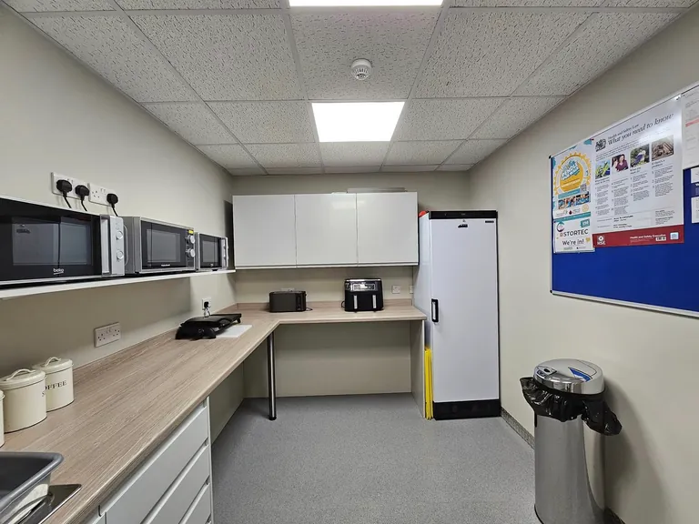 White-painted staff kitchen with fitted units and a suspended ceiling