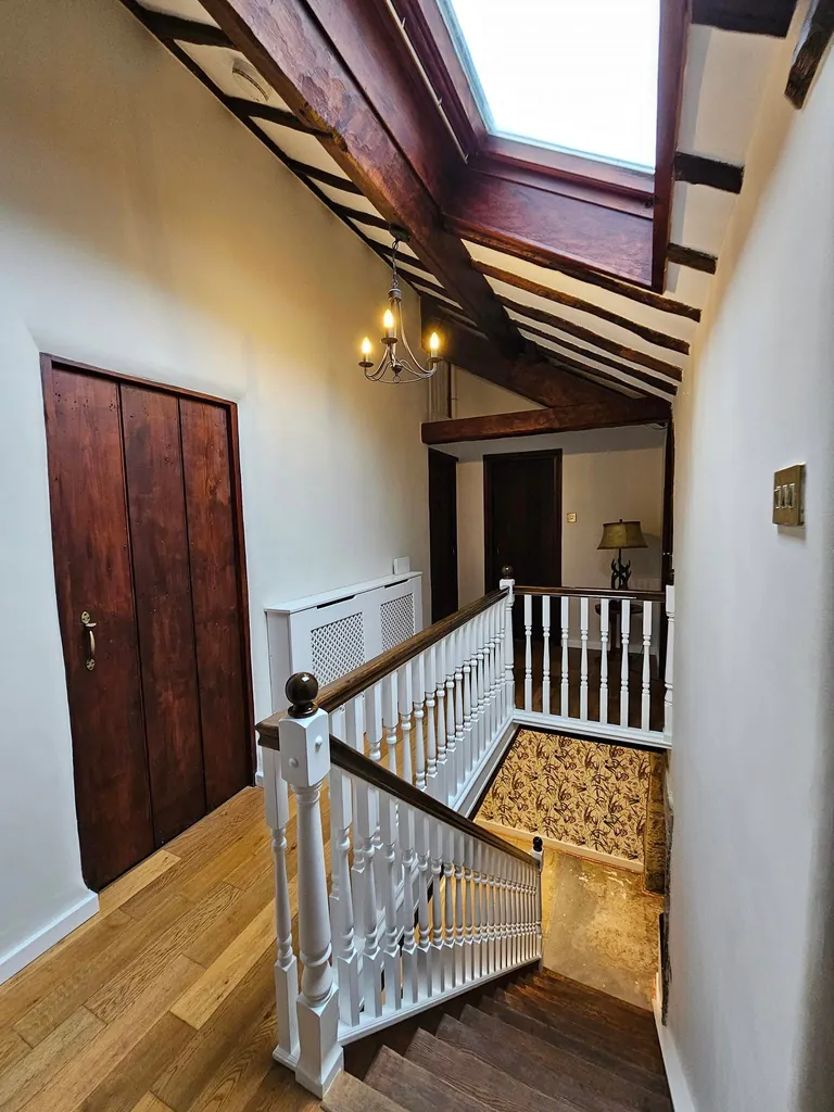 Decorated landing with white walls, wooden doors and exposed roof beams
