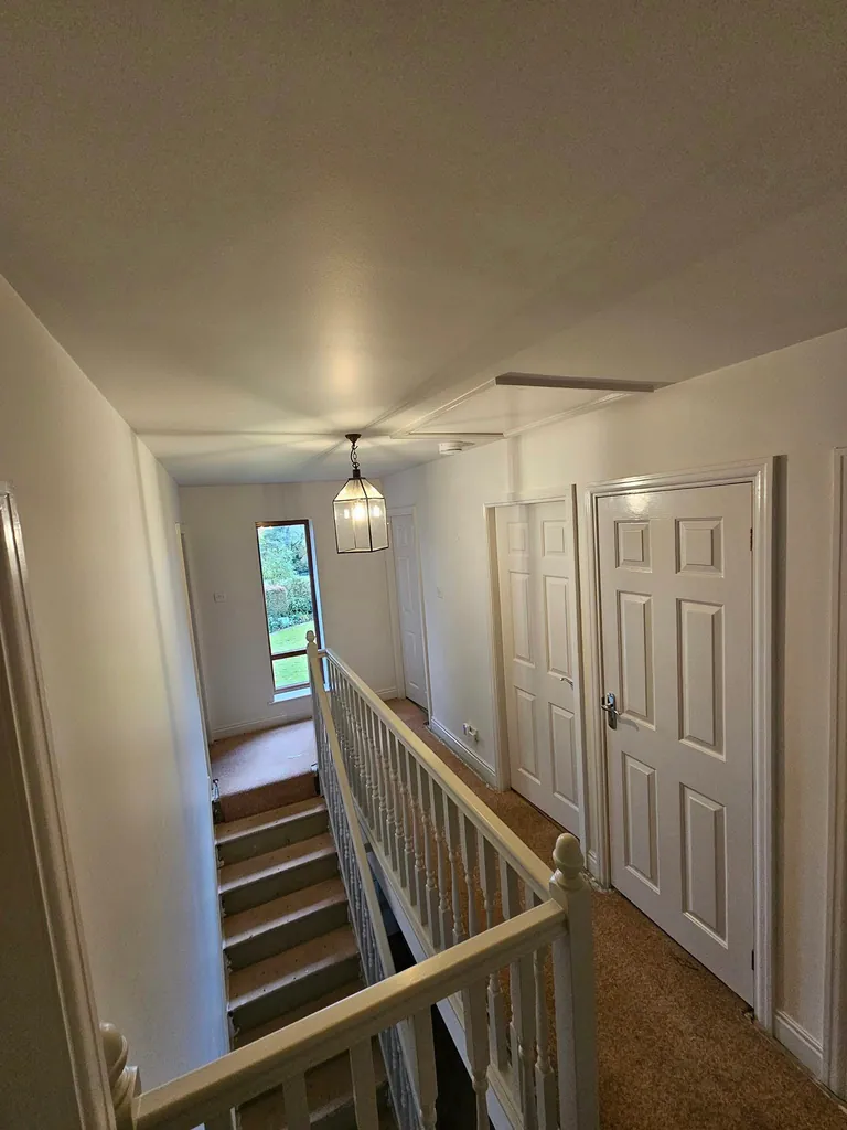 Upstairs landing with pale walls, white doors and a wooden handrail
