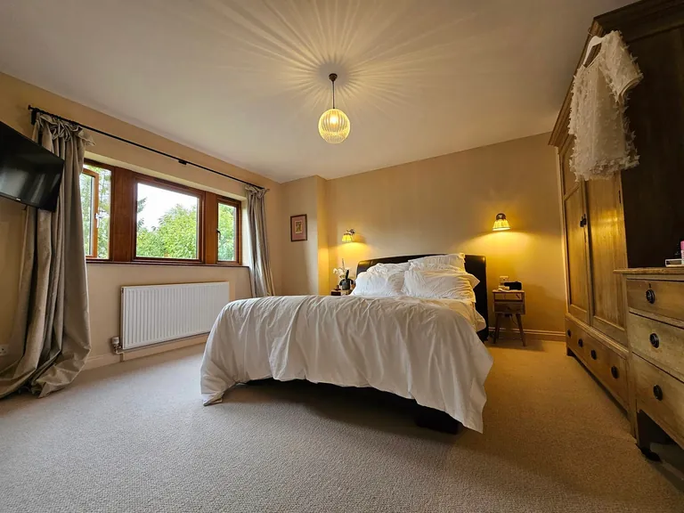 Bedroom with warm neutral walls, wooden furniture and a white ceiling