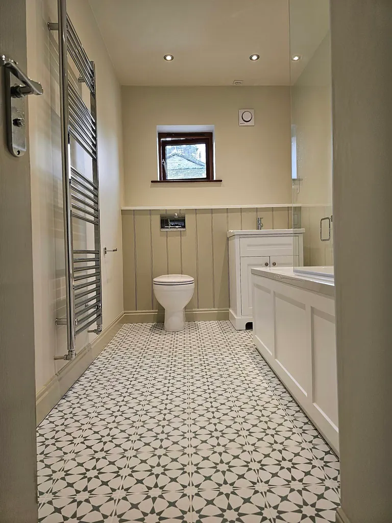 Bathroom with painted wall panelling, white vanity unit and patterned floor tiles