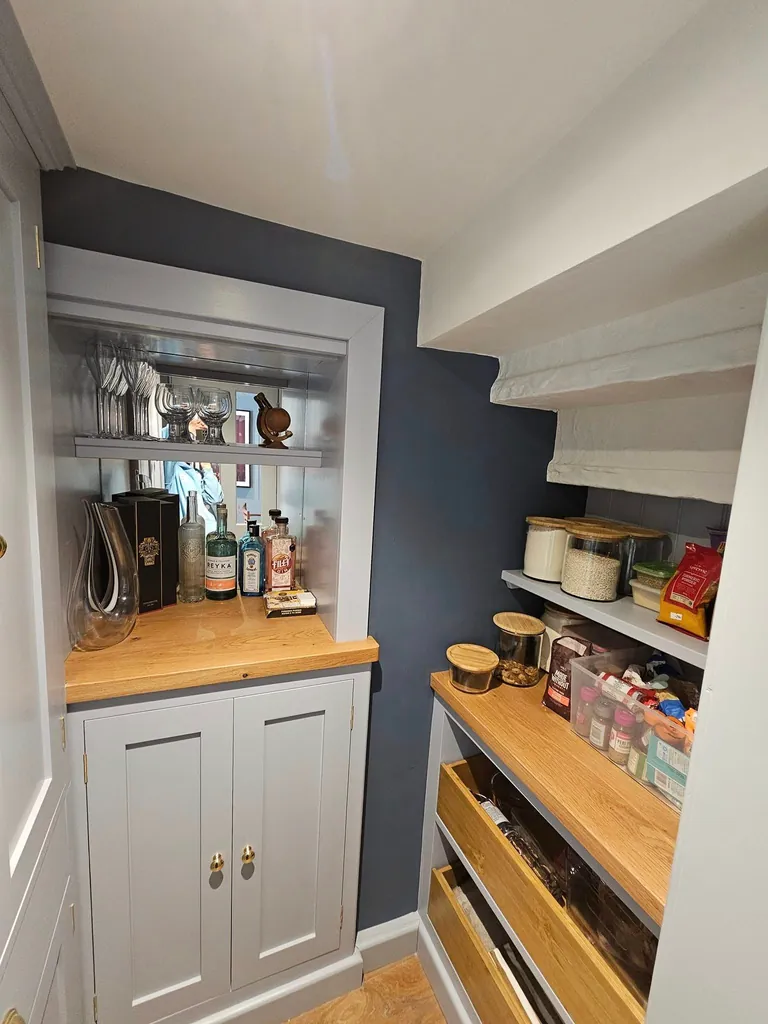 Pantry with dark blue walls, grey cabinets and wooden worktops